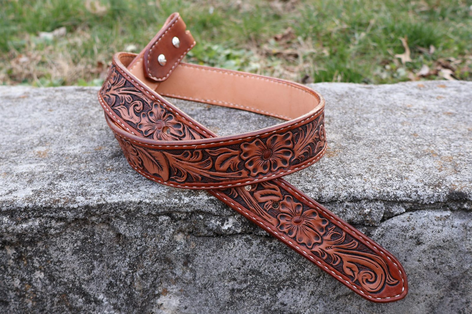 Hand tooled floral leather belt on stone